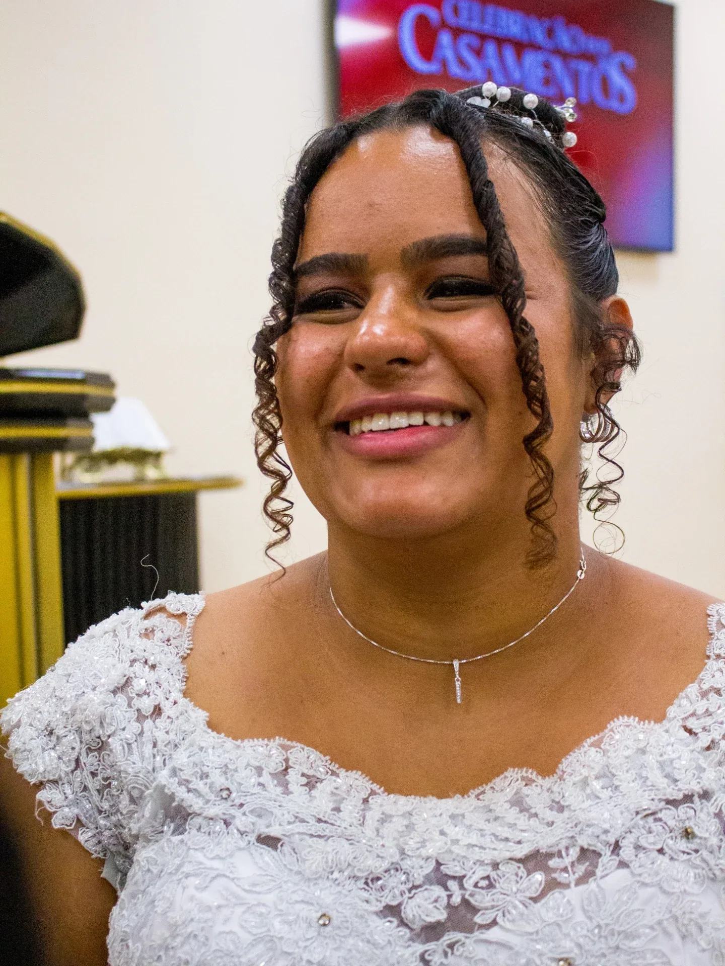 Noiva de vestido rendado sorri para a câmera.
